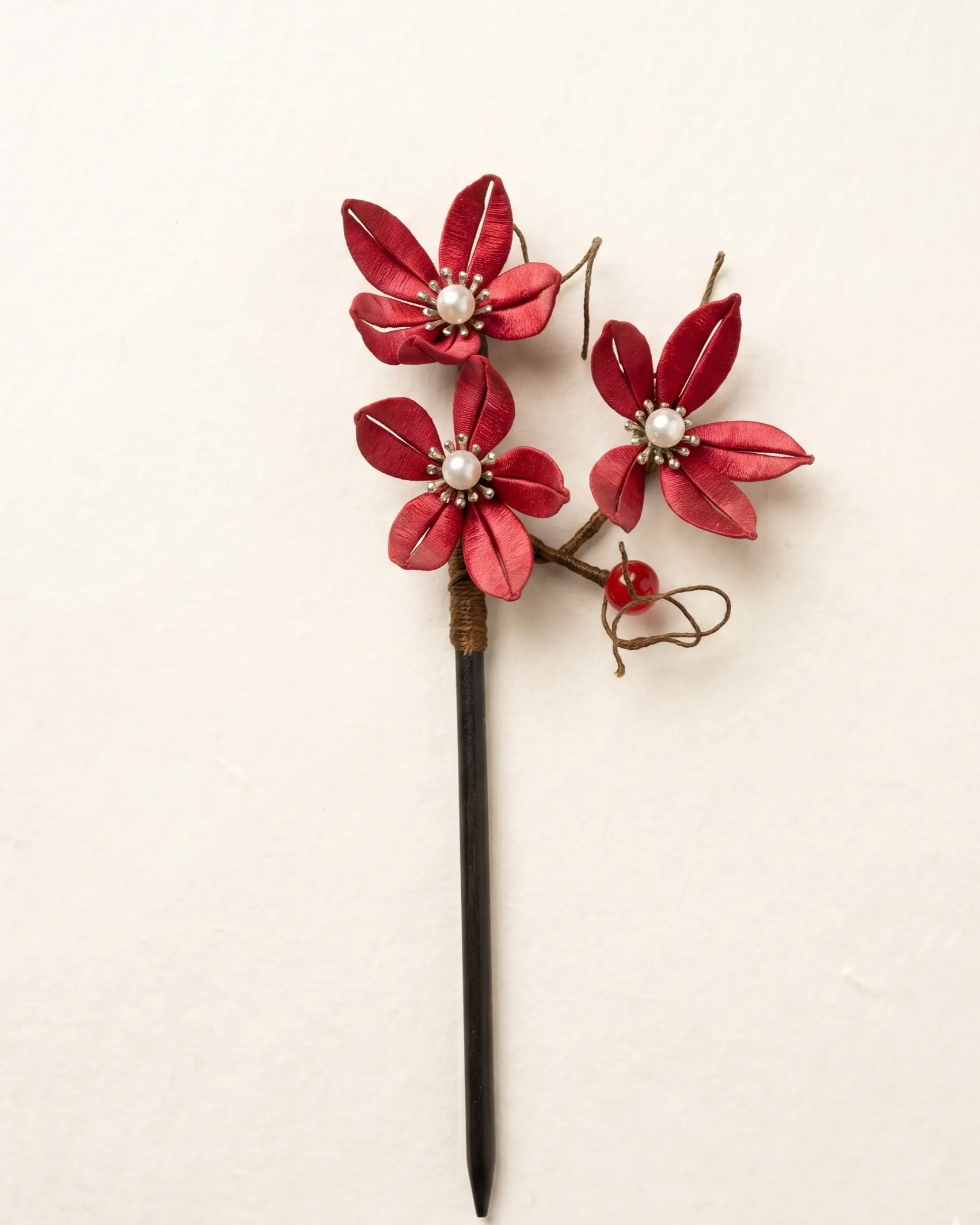 Plum blossom motif in red silk-wrapped chanhua — symbol of resilience
